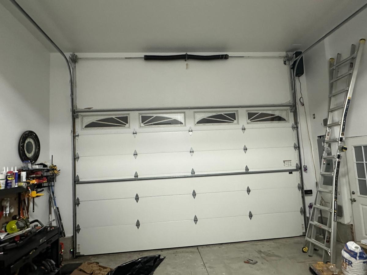 Finished white double garage door with decorative top windows in residential garage
