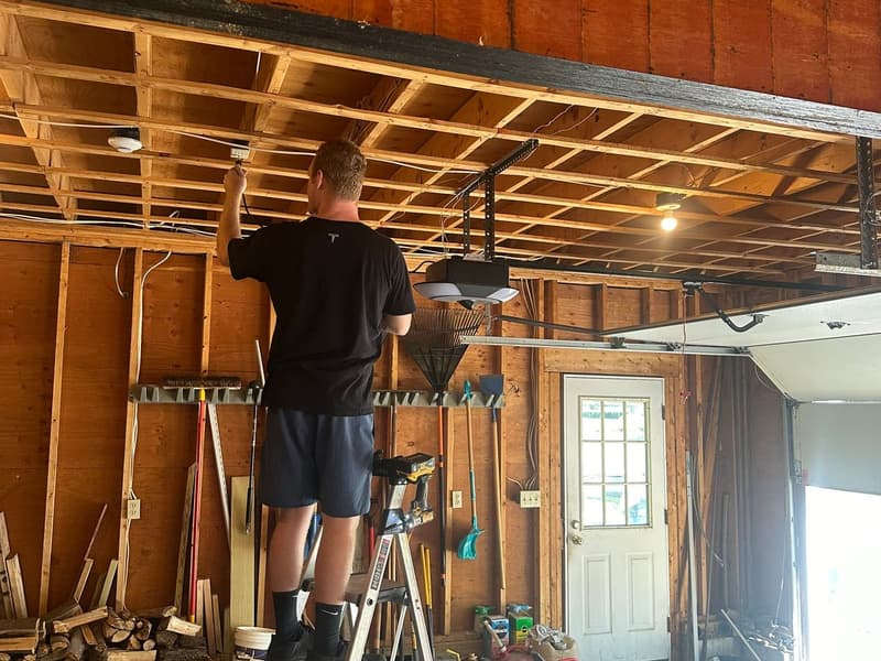 Murray technician on ladder performing spring repair in residential garage